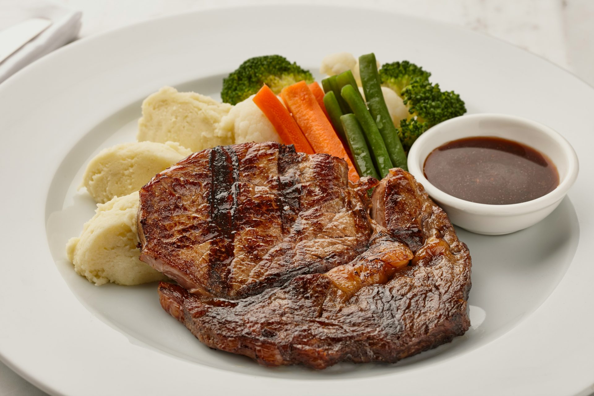 Grilled steak with mashed potatoes and vegetables.